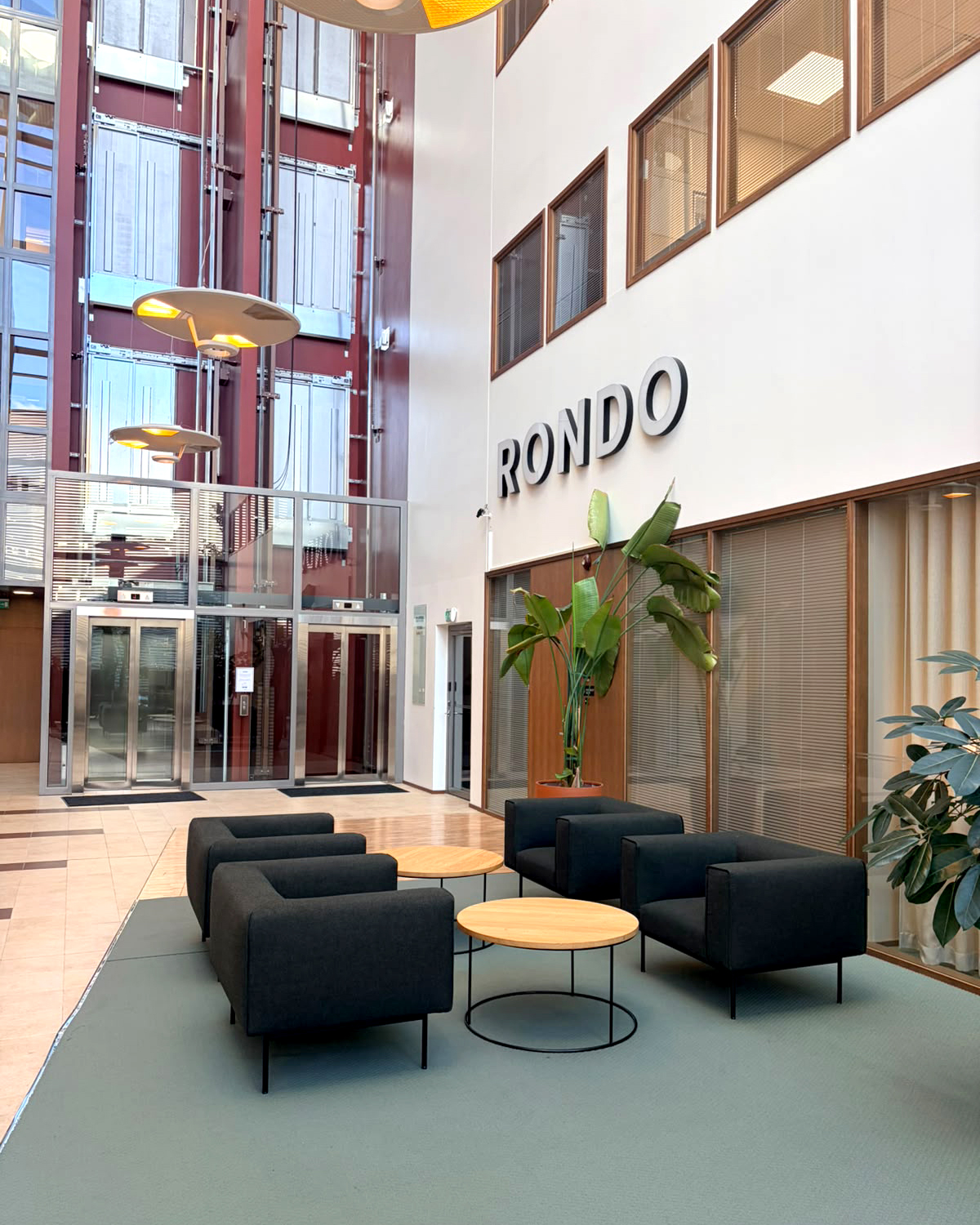 Rondo-rakennuksen aula Vantaalla, jonne Finspectionin Helsingin toimisto muutti. Aulassa nojatuoleja, pyöreitä pöytiä ja lasiset hissit.